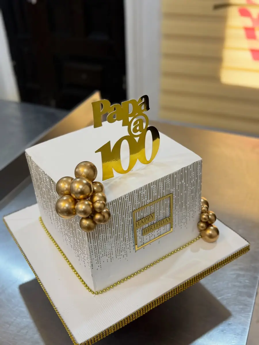 Two-tier gold and white cake for a 100th birthday