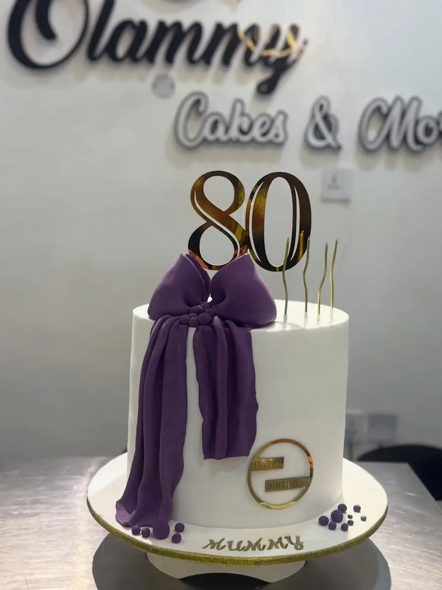 Purple and white 80th birthday cake with a large bow